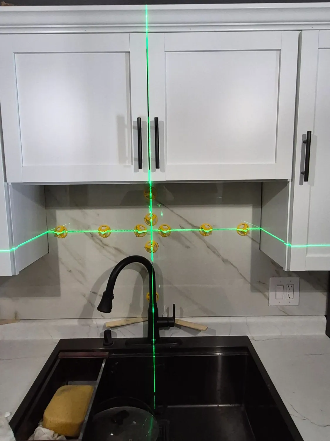White cabinets being installed with a laser level